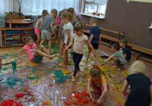 Dzieci chodzą po kolorowym makaronie